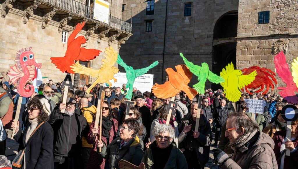 Manifestantes contra Altri en Compostela, levando paxaros de cores de cartón